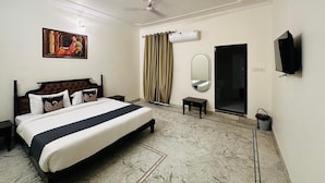 A hotel room with a bed, a television, a mirror, and a window with curtains.