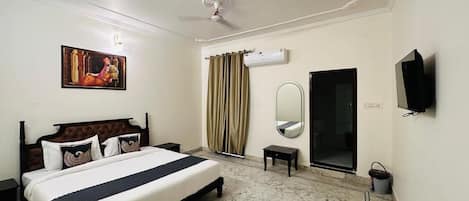 A hotel room with a bed, a television, a mirror, and a window with curtains.