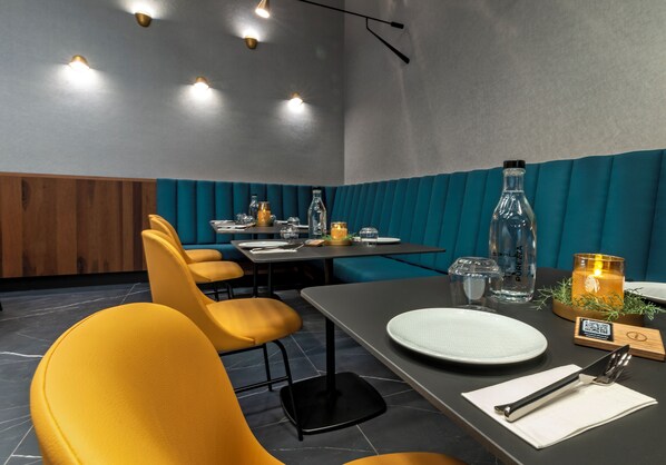 A restaurant interior with yellow chairs, a table set for dining, and a teal-colored wall.