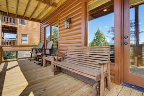 Eine Holzterrasse mit Bänken und Geländer, mit Blick auf ein bewaldetes Gebiet.
