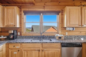 A kitchen with wooden cabinets, a granite countertop, a stainless steel sink, and a dishwasher. - New Listing, Game Room, Theater Room, Free Attractions (Sevierville)