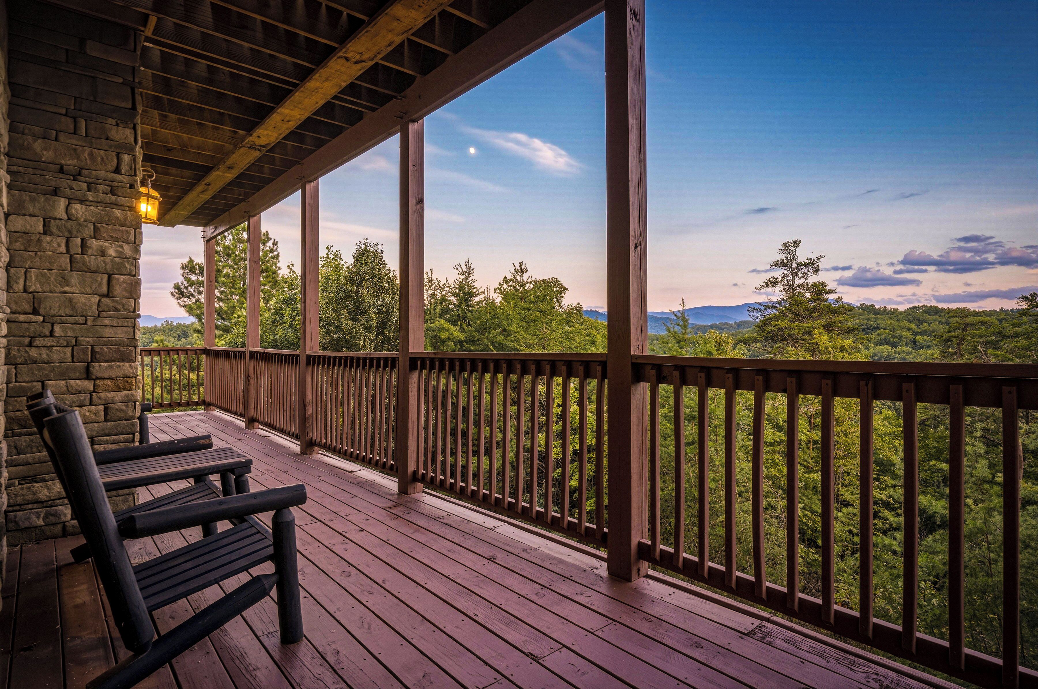A wooden deck with a railing, benches, and a stone wall.