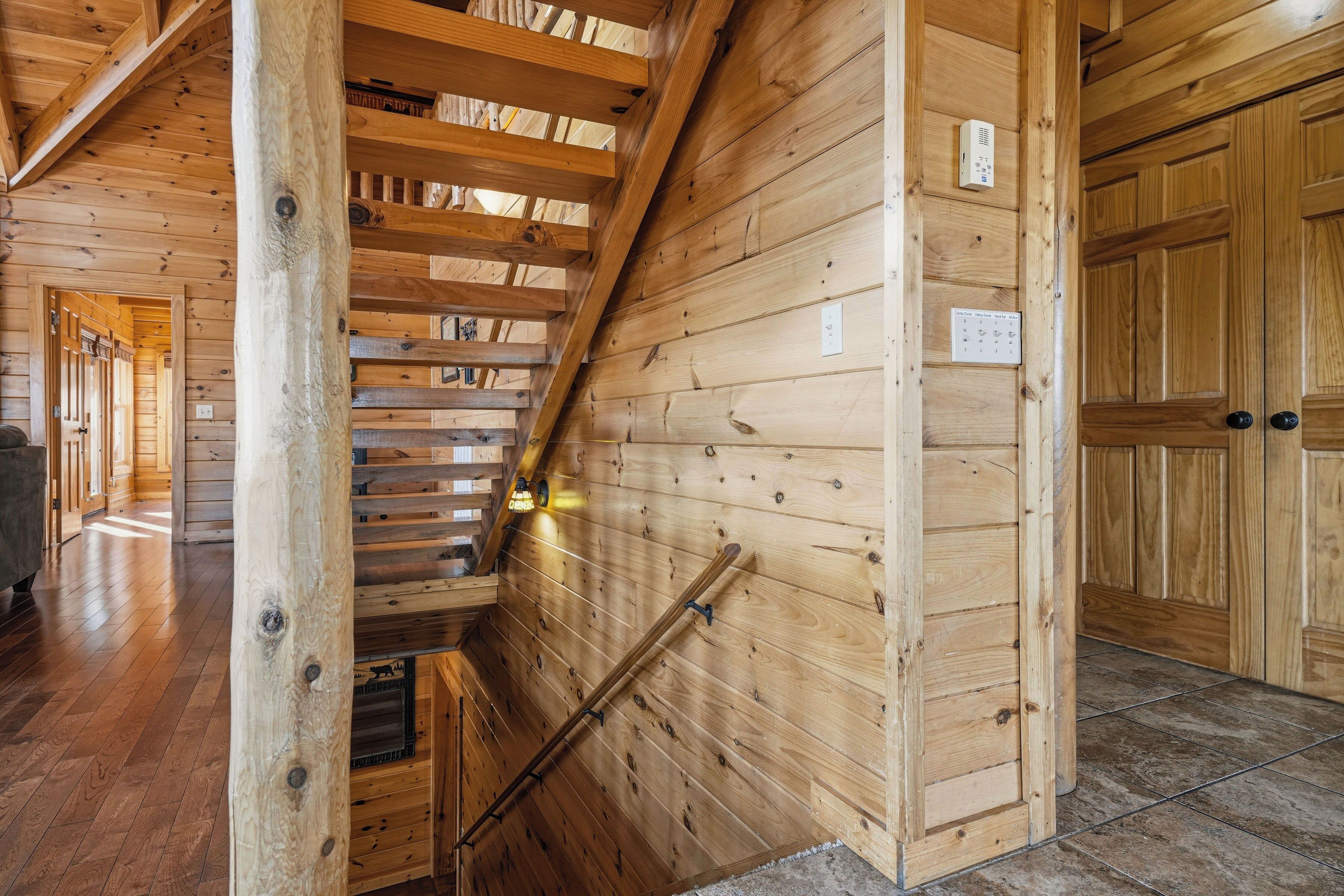 Un intérieur en bois avec un escalier, des murs en bois et une porte sur laquelle est apposée une enseigne.