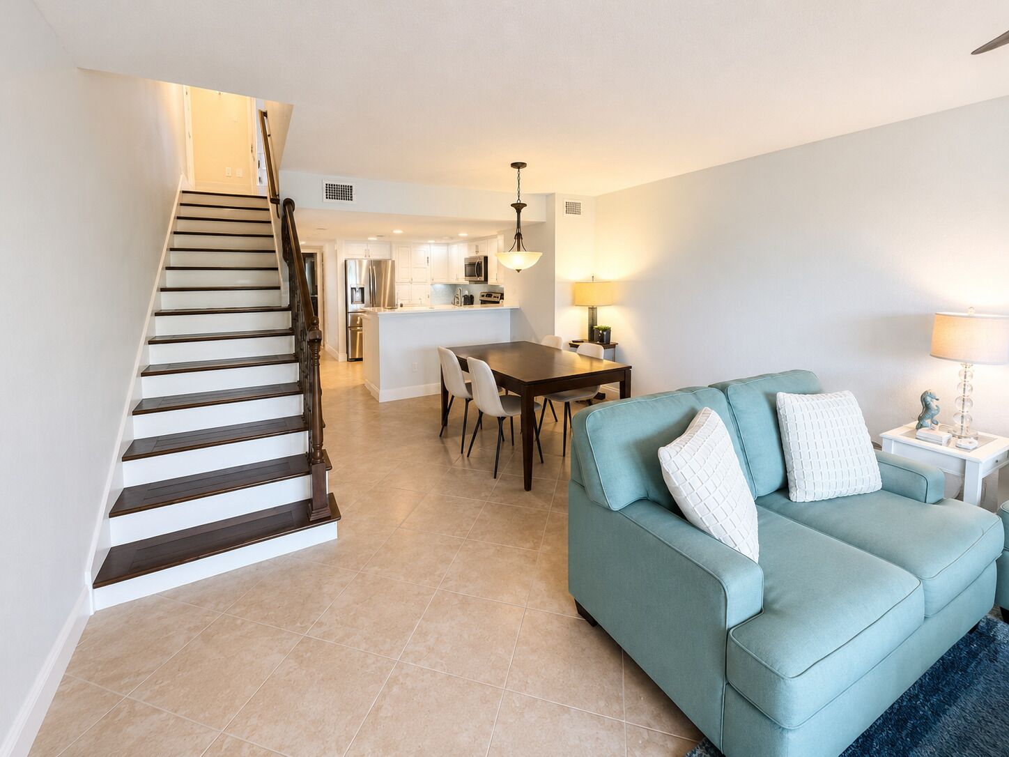 A modern interior with a staircase, a dining area, and a living room with a sofa.