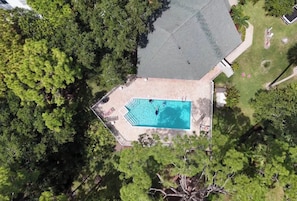 Vista aèria d'una propietat amb piscina, rodejada d'arbres, zona de terrassa coberta i pati tancat per una tanca.
