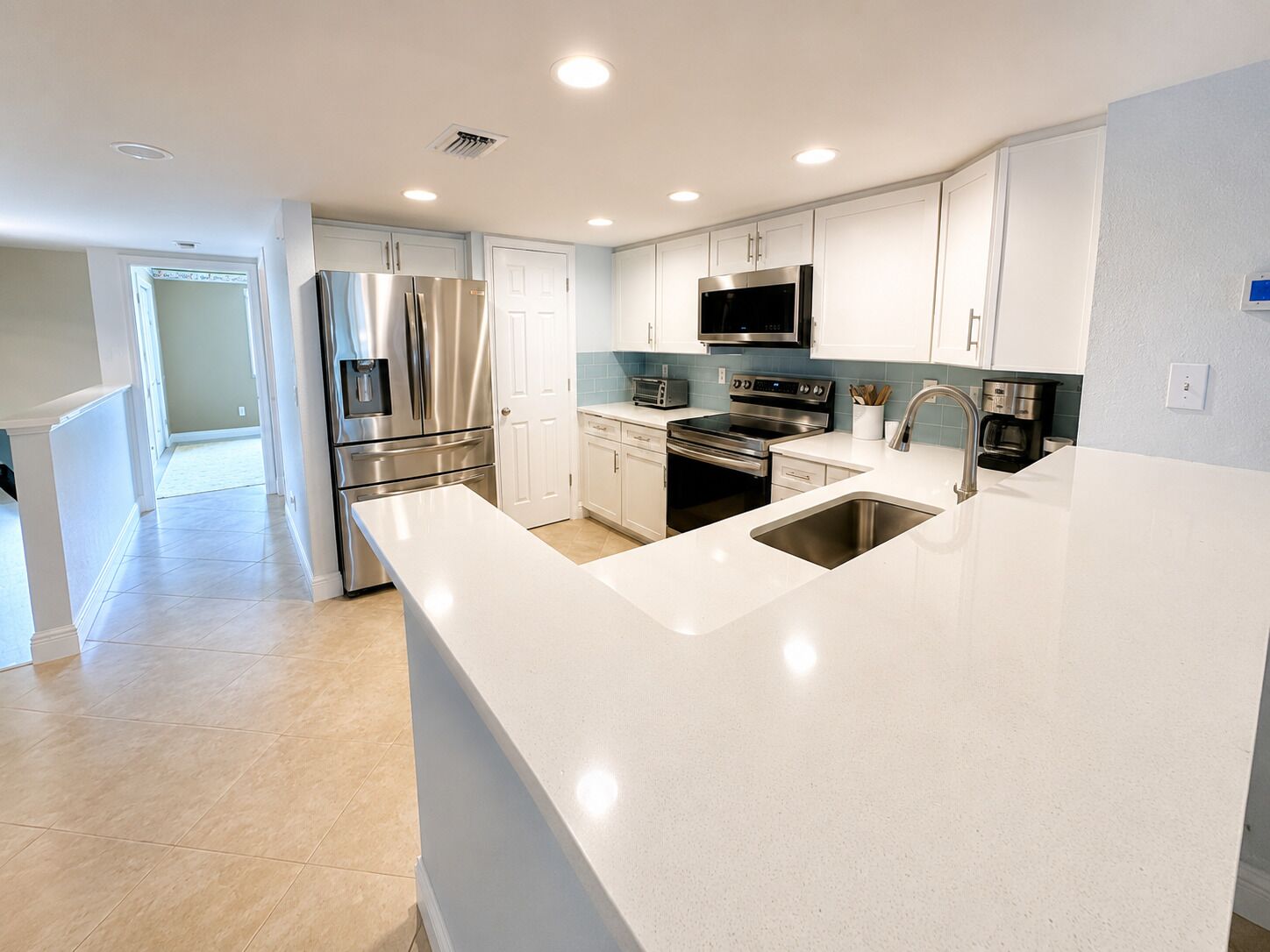 A modern kitchen with stainless steel appliances, a large island with a sink, and a microwave above the stove.