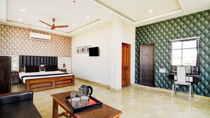 A hotel room with a bed, a desk, a chair, a coffee table, and a TV. - Collection O Howrah Botanical Garden (Howrah)