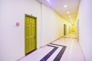 Un pasillo con una puerta verde, paredes blancas y suelo de baldosas.