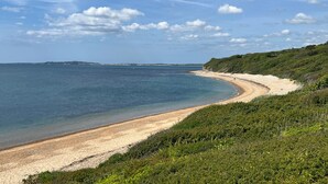 Eine Küstenlandschaft mit sandigem Strand, blauem Himmel und einer fernen Küstenlinie.