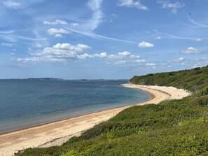 Eine Küstenlandschaft mit sandigem Strand, blauem Himmel und einer fernen Küstenlinie.
