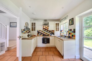 A kitchen with white cabinets, a colorful backsplash, a microwave, and a window with a view of greenery. - The Old Coach House -  Ansty, Dorchester sleeps 4 guests  in 2 bedrooms (Ansty)