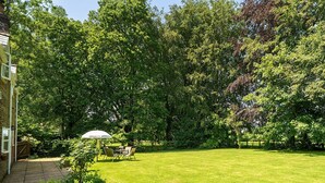 Ein gepflegter Rasen mit einer Terrasse, einem Esstisch und Stühlen.