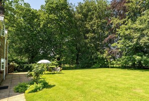 Ein gepflegter Rasen mit einer Terrasse, einem Esstisch und Stühlen.