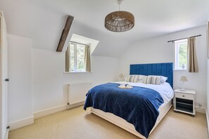 Ein Schlafzimmer mit einem Bett, einem Nachttisch, einer Lampe, einem Fenster und einer Heizung.