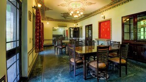 A dining area with a large table and chairs, ornate ceiling, and traditional decor. - Super Collection O Mall  (Jaipur)