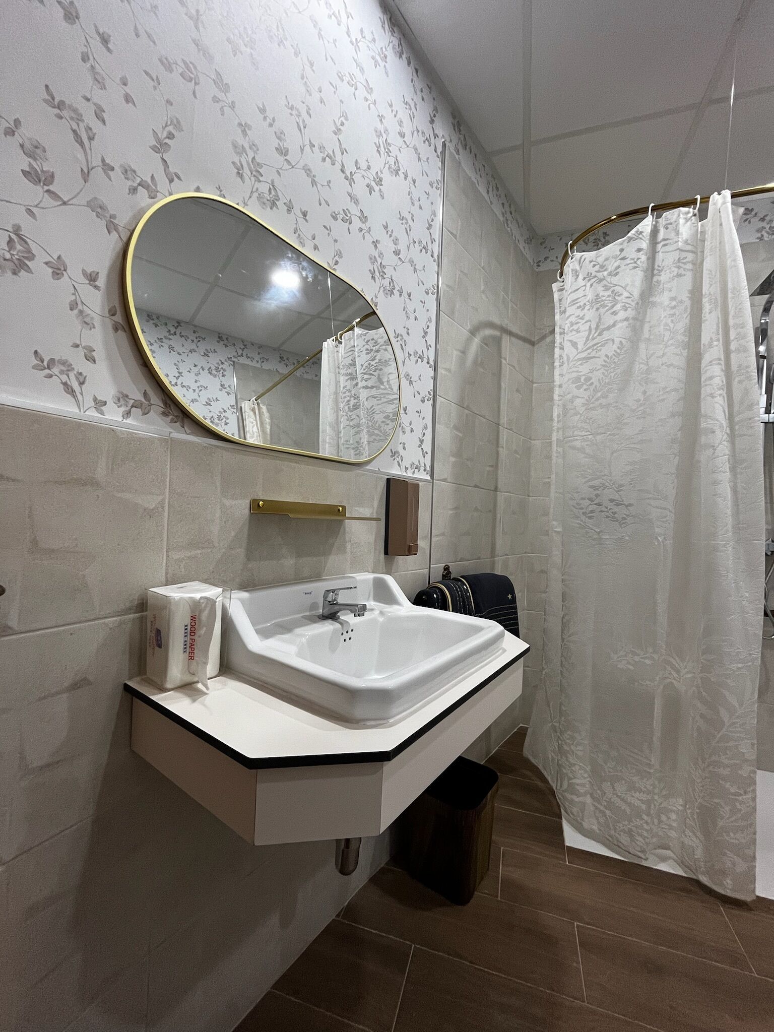 Un baño con lavamanos blanco, un espejo y una cortina de ducha.