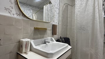 Un baño con lavamanos blanco, un espejo y una cortina de ducha.
