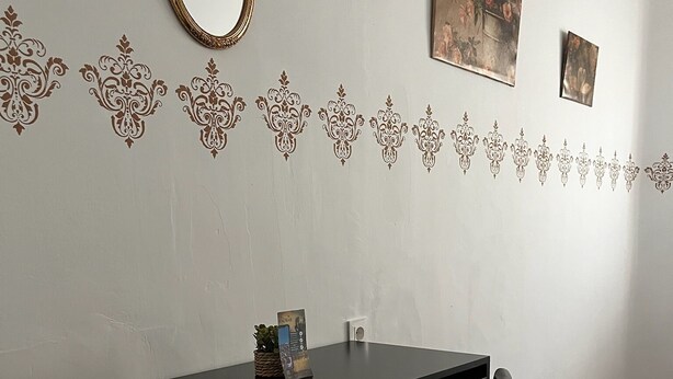 A room with a dark wooden desk, a chair, a mirror, and decorative wall stickers. - Pensión El Palmar  (Tobarra)