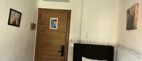 Habitación de hotel con cama, escritorio, puerta y lámpara en el techo.