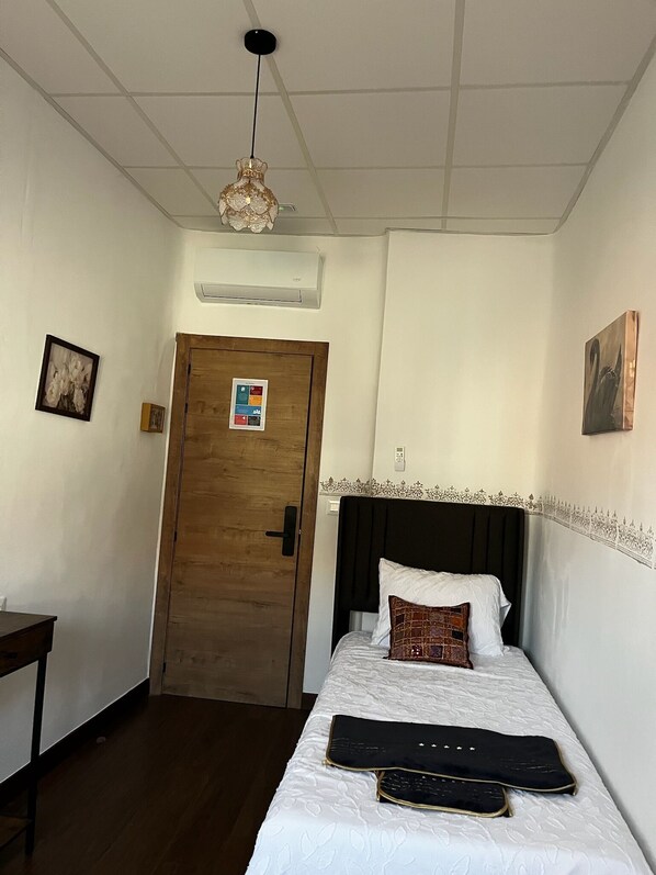 A hotel room with a bed, a desk, a door, and a ceiling light fixture. - Pensión El Palmar (Tobarra)