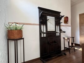 Una puerta de madera tradicional con una cesta de flores sobre un soporte a la izquierda.
