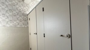 A restroom with three doors, a bench, and patterned wallpaper. - Pensión El Palmar  (Tobarra)