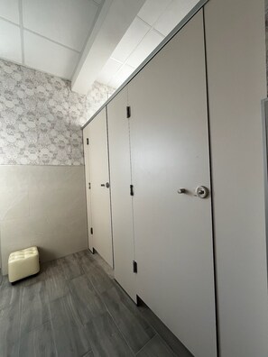 Baño con tres puertas, un banco y papel tapiz estampado.