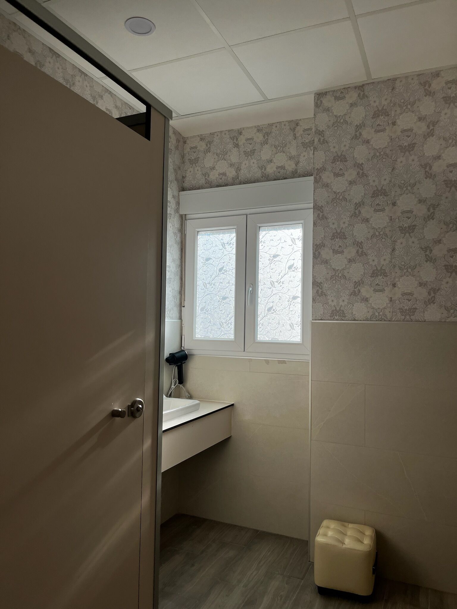 Un baño con ventana, lavamanos e inodoro.