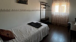 A single-bed room with a bunk bed, a hanging light fixture, a painting on the wall, and a window with curtains. - Pensión El Palmar  (Tobarra)