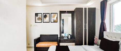 A modern hotel room with a bed, a sofa, a desk, and a wardrobe.