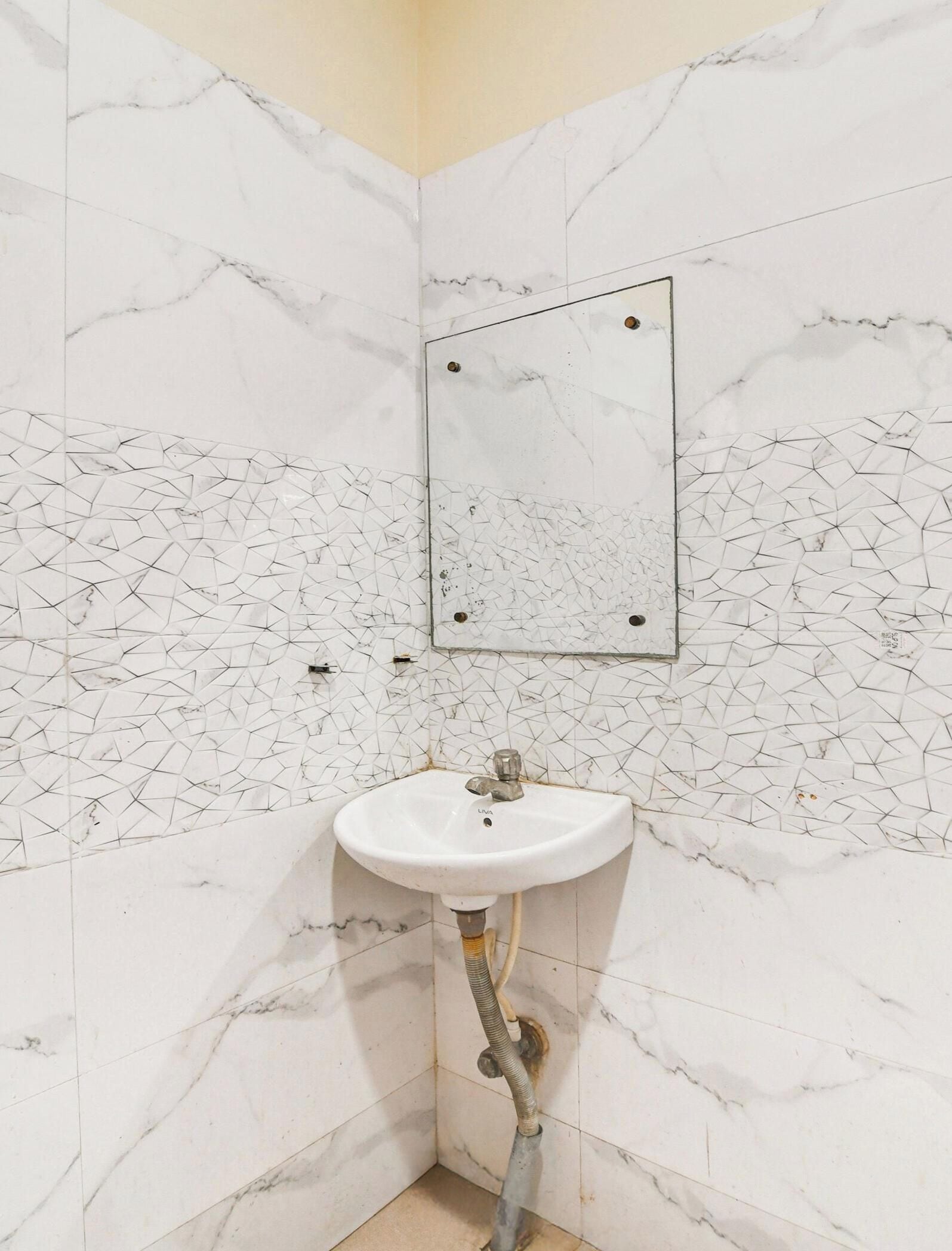 Un bagno con un lavabo in marmo bianco, uno specchio e una parete rivestita di piastrelle con motivo geometrico.