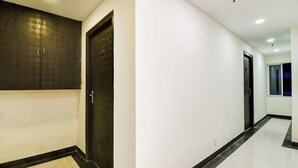 A hallway with a dark-colored door and a white wall. - Super Collection O City Center 2 (Barasat)
