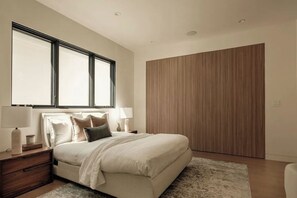 A bedroom with a bed, nightstands, lamps, a large window, and a wooden wardrobe. - Lemmer Estate - Tarzana Golf Course Home with Indoor Pool (Tarzana)