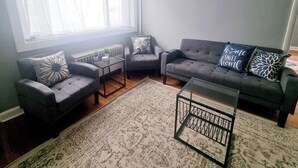 A living room with a grey sofa, two armchairs, a coffee table, and a patterned rug. - Inviting 1BR Apartment — Rockledge Location (Rockledge)