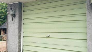 Een garage met een groene deur, een betonnen muur en een metalen dak.