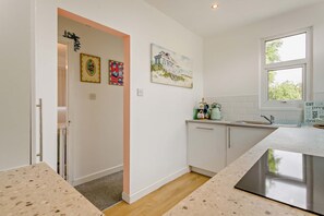 A modern kitchen with a countertop, sink, and cabinets. There are two framed artworks on the wall. - Host Stay Ocean Tao (Clacton-on-Sea)