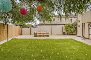 A backyard with a lawn, a wooden fence, and a table with chairs. - Host Stay Ocean Tao (Clacton-on-Sea)