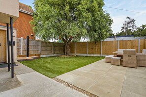 A backyard with a lawn, a wooden fence, a tree, and outdoor furniture. - Host Stay Ocean Tao (Clacton-on-Sea)