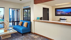 A reception area with a blue sofa, a glass coffee table, a framed picture, and a TV displaying a coastal scene. - 2 Units | Seaport Village Stay Avalon Waterfront Views (Avalon)