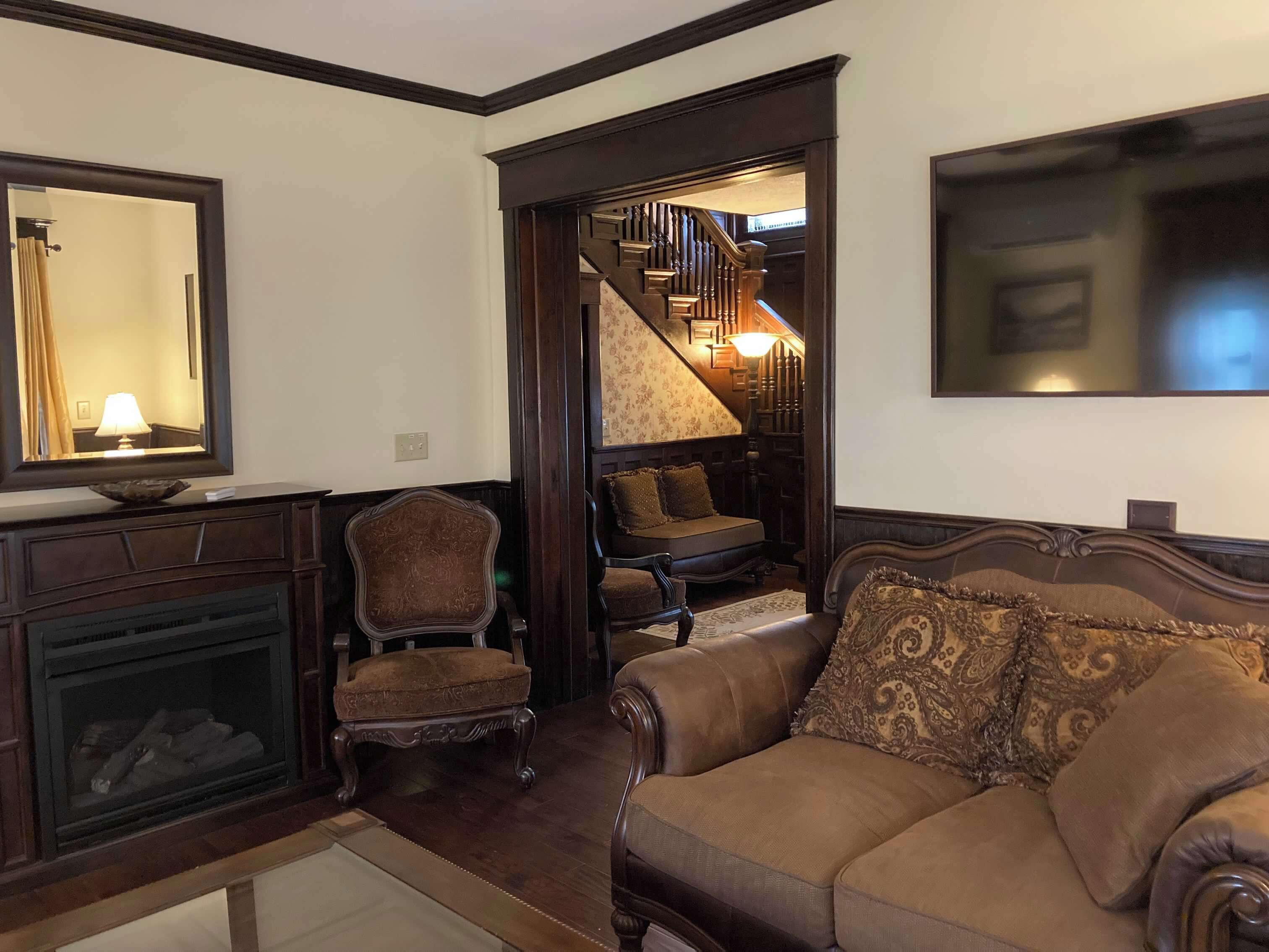 A living room with a fireplace, a sofa, a chair, and a staircase leading to an upper level.