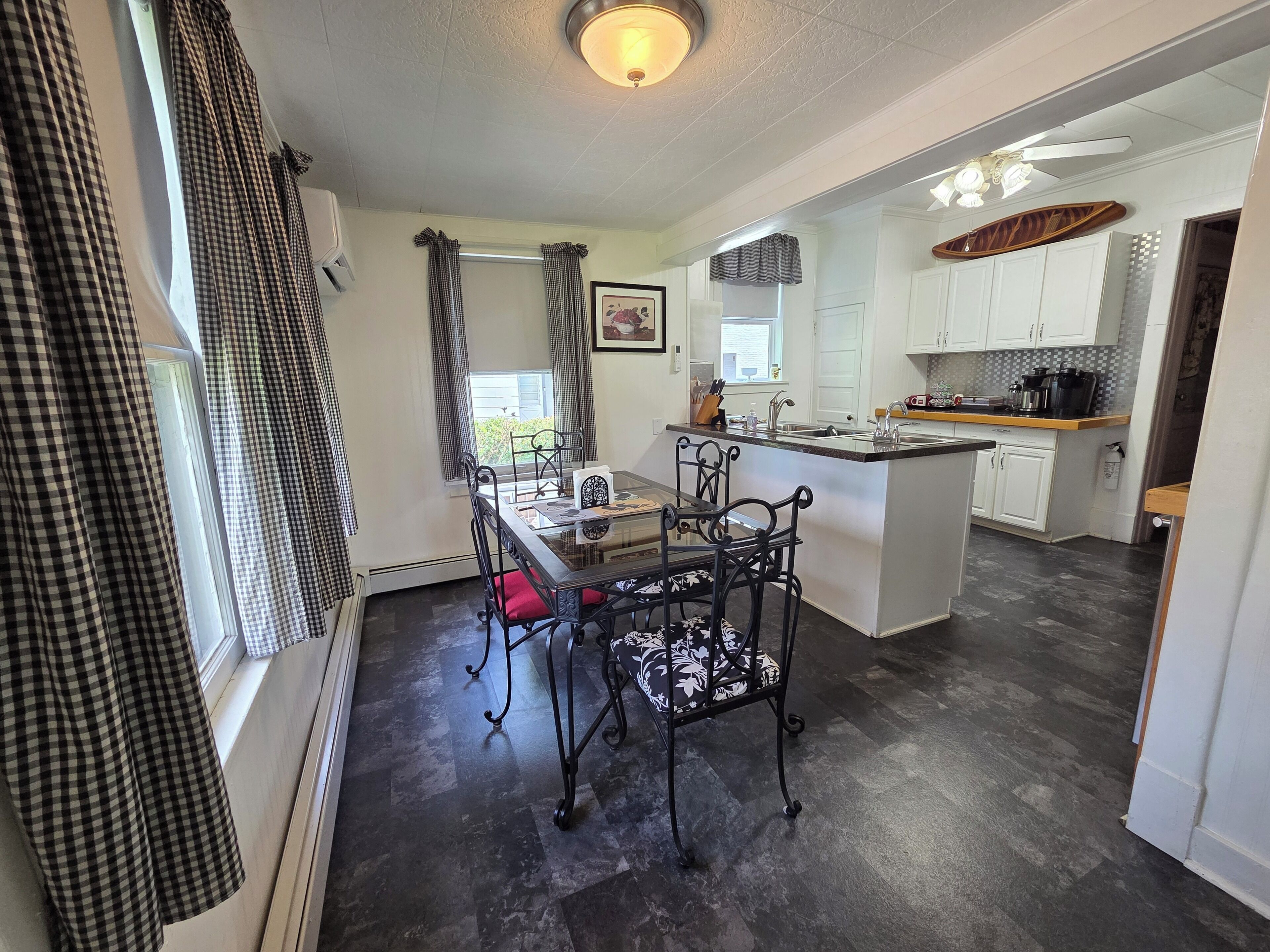 A kitchen with a central island, white cabinetry, and a dining area with a table and chairs.