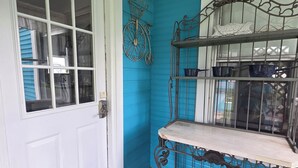 A corner of a room with a white door, a blue wall, a metal shelf with items, and a doormat with a bicycle symbol. - Grand Victorian - Easy GAP Access, shops, and restaurants (Confluence)