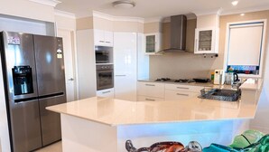 A modern kitchen with stainless steel appliances, a central island, and a glass vase. - Bluewater Sanctuary: Luxury Beach house with private jetty (Tascott)