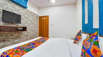 Una habitación con una cama, un televisor montado en una pared de ladrillo y una puerta.
