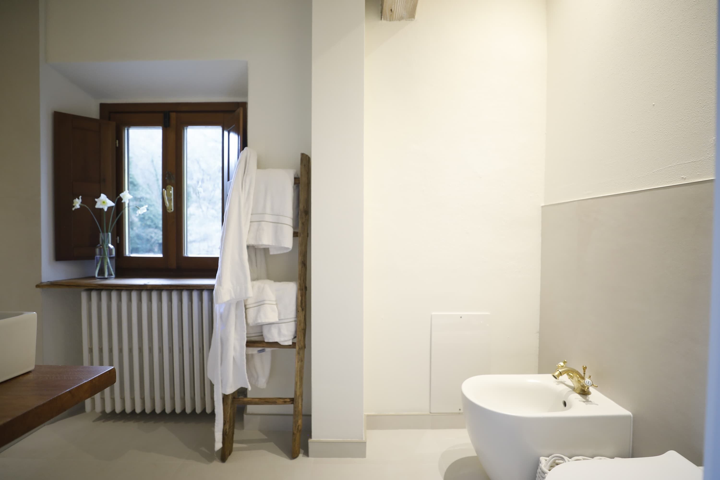 Ein Badezimmer mit einem weißen Waschbecken, einer Badewanne und einem Holzboden mit Handtüchern.