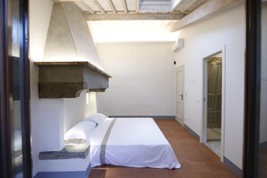Ein kleiner, abgeschlossener Raum mit einem Bett, einer Dusche und einer Tür zu einem weiteren Raum.