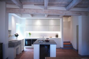 Una cocina moderna con muebles blancos, una isla central y un horno empotrado.