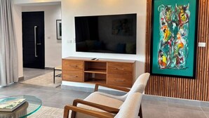 Una sala de estar moderna con televisor de pantalla plana, mueble de entretenimiento de madera y un cuadro abstracto colorido.