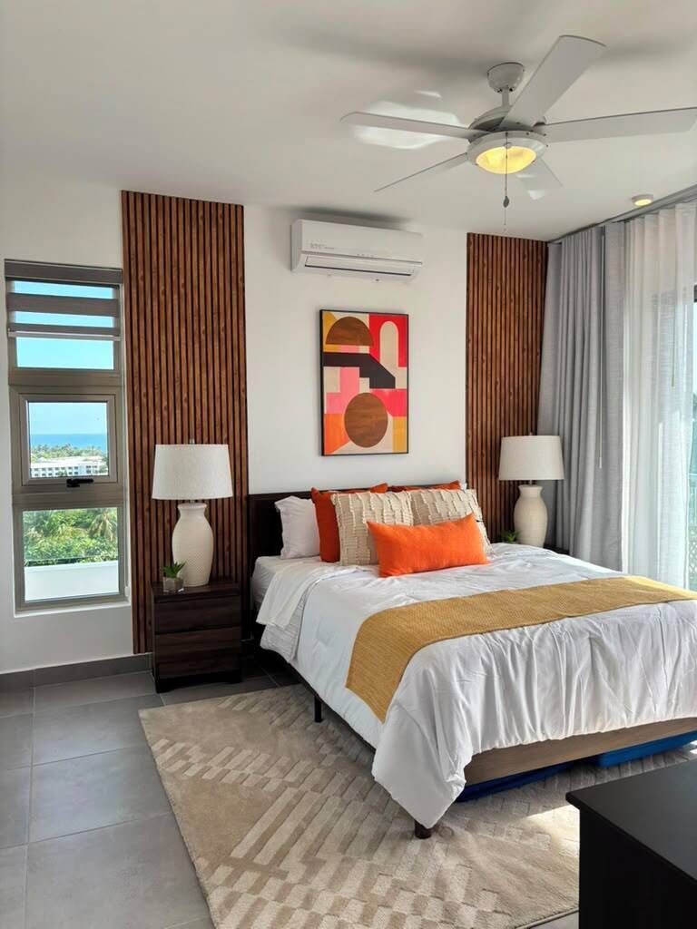 Ein modernes Hotelzimmer mit einem großen Bett, einem Deckenventilator, einem Fenster mit Blick und einer wandmontierten Klimaanlage.