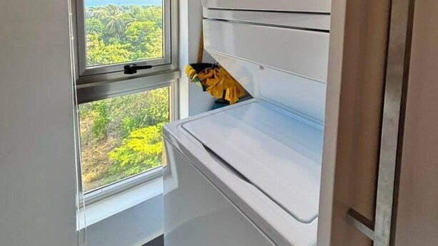 Una cocina compacta con horno integrado y una ventana con persianas.